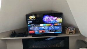 Televisor de pantalla plana en un estante mostrando diferentes servicios de streaming.