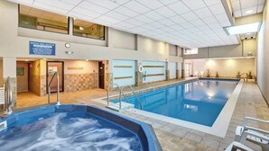 Una amplia piscina interior con una zona de hidromasaje separada, una recepción e indicación de la ubicación.