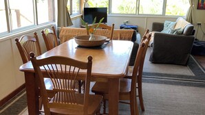 Zona pranzo con tavolo e sedie in legno, televisione e divano.