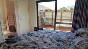 Een slaapkamer met een bed, een badkamer en uitzicht op de achtertuin.