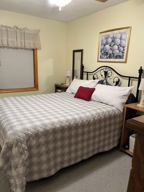 Cozy bedroom with a large bed, nightstands, and a framed floral artwork.