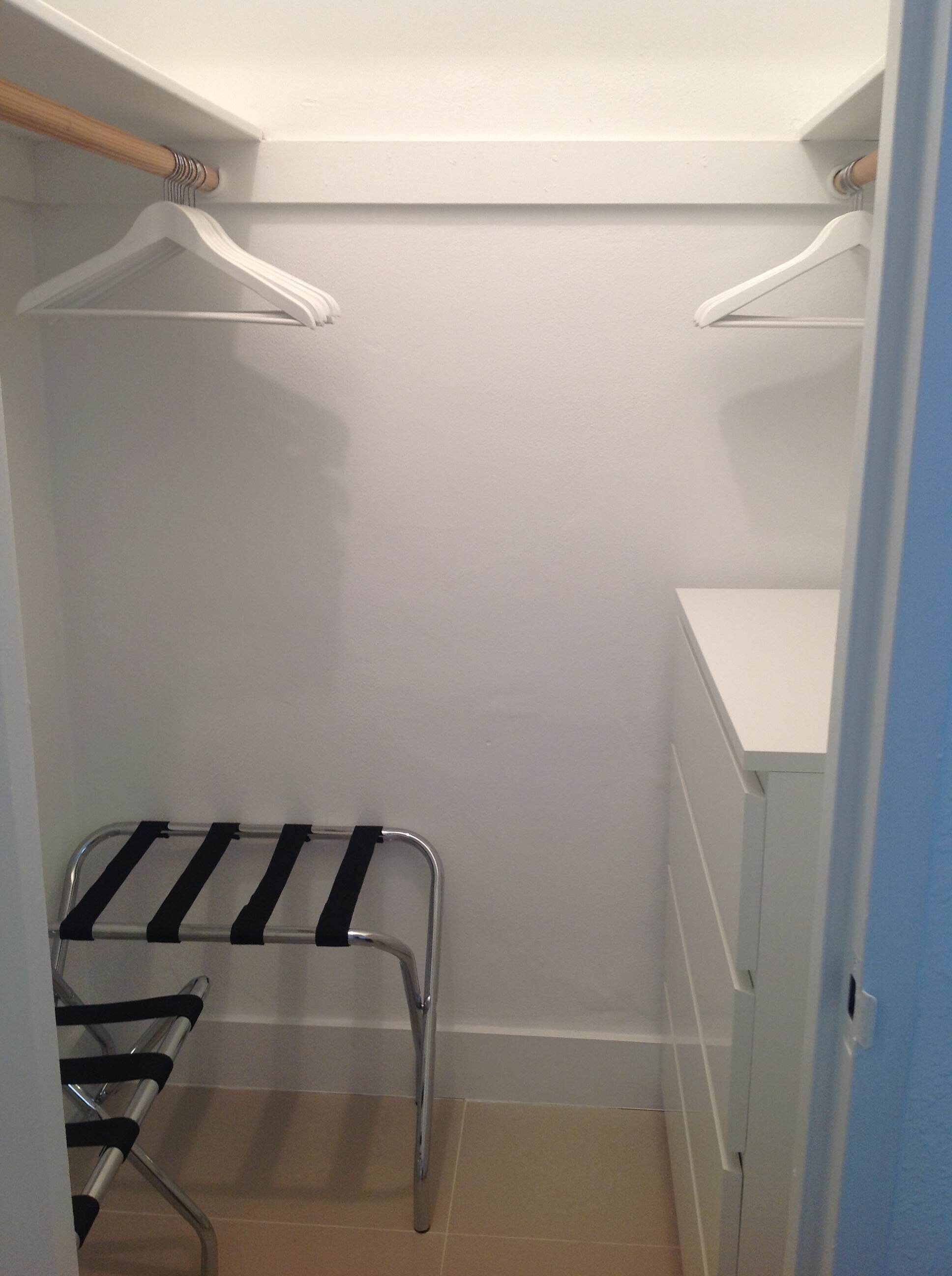 A walk-in closet with a metal drying rack, white shelves, and a blue door.