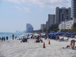 Une plage où l’on peut voir des gens se prélasser au soleil, des parasols et des chaises de plage.