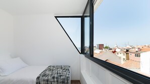 A small, bright room with a bed and a window overlooking a cityscape. - A pearl of an apartment in Belém (Lisboa)
