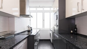 A modern kitchen with a dishwasher, washing machine, and stainless steel appliances. - A pearl of an apartment in Belém (Lisboa)