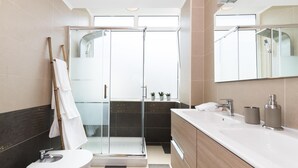 A modern bathroom with a glass-enclosed shower, a toilet, a vanity with a sink, and a large mirror. - A pearl of an apartment in Belém (Lisboa)