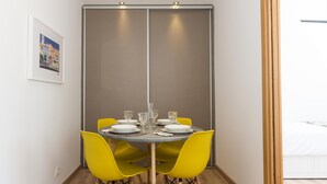 A dining area with a round table set for six, yellow chairs, and a sliding door in the background. - A pearl of an apartment in Belém (Lisboa)