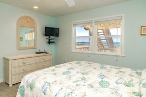Un dormitorio con cama, cómoda, televisor y ventana con vista al muelle.