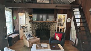 A cozy living room with a stone fireplace, comfortable seating, and a staircase. - Adorable 3 bed cottage - 2 blocks to private beach; pond; AC, pets ok (Plymouth)