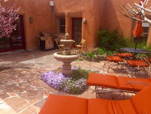 A patio with stone flooring, a stone fountain, orange lounge chairs, and a barbecue grill. - Beauty and Comfort- Location-Enclosed Patio-Hot Tub - Last  Min.449nt! (Santa Fe)