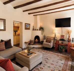 A cozy living room with a fireplace, a sofa, a coffee table, and a television.