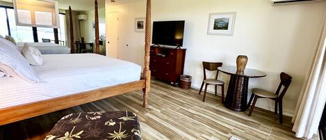 Una habitación de hotel con cama, escritorio, silla, televisor y ventana.