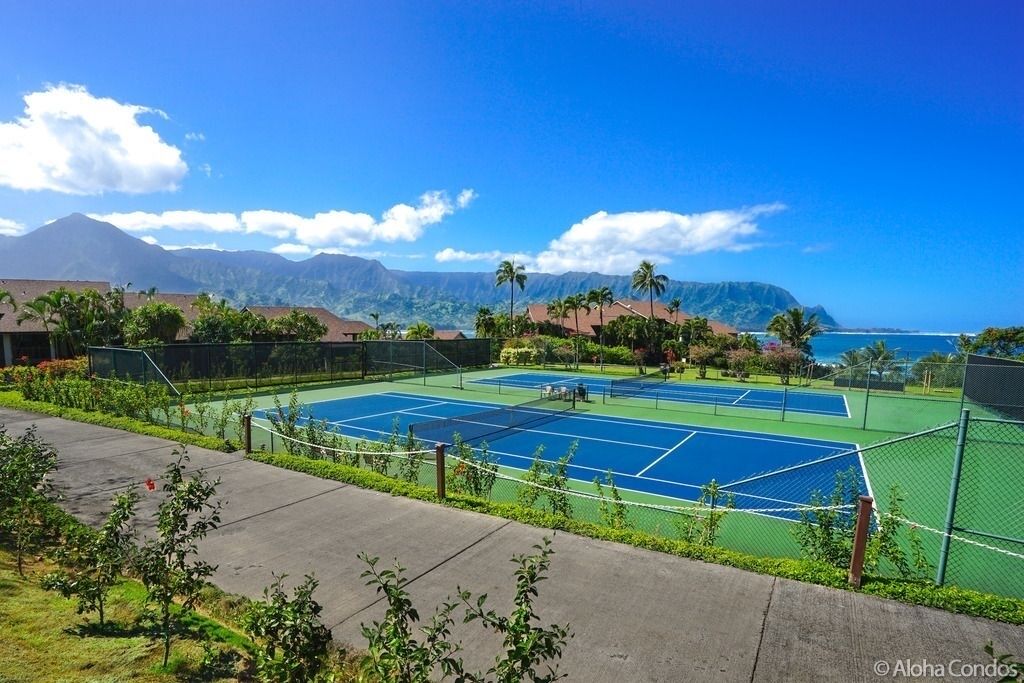 Una cancha de tenis con vistas a montañas y al océano.