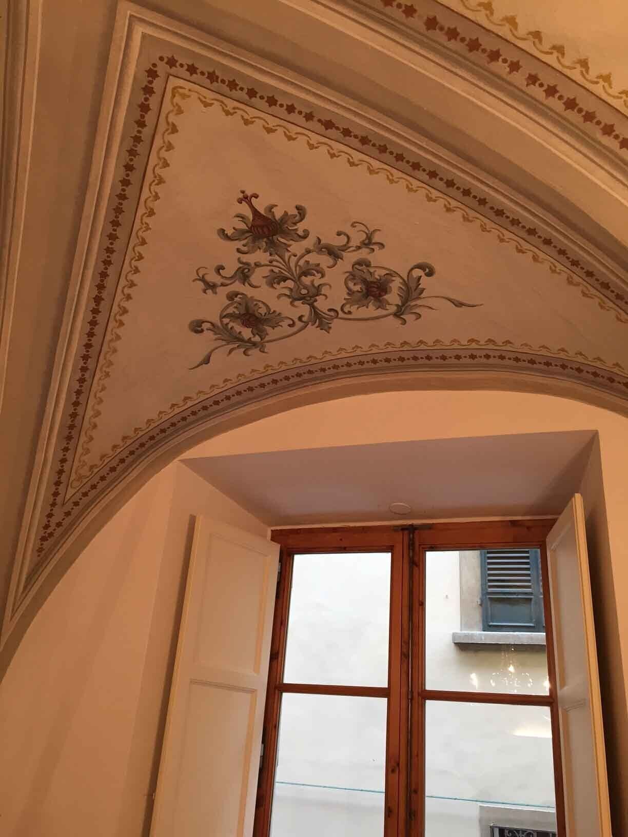 An arched doorway with a decorative ceiling featuring floral patterns.