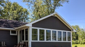 Une maison avec un porche abrité, une pelouse et des arbres en arrière-plan.