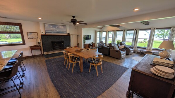 A spacious living room with a fireplace, a dining area, and a seating area with sofas and chairs.