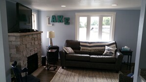 A living room with a stone fireplace, a leather sofa, and a window with a view.