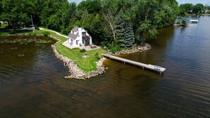 A lakeside house with a dock, surrounded by lush greenery and a calm lake.