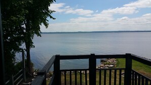 A wooden deck overlooking a calm lake with distant land visible on the horizon.