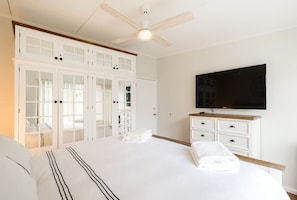 Ein Schlafzimmer mit Bett, Kleiderschrank, Fernseher und Deckenventilator.