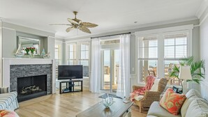 A spacious living room with a fireplace, a television, and a view of the outdoors. - The Original Lulla-by the Sea Amazing Oceanfront Beach House W/Pool and Elevator (Carolina Beach)