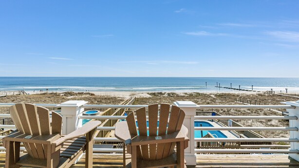 Two Adirondack chairs on a wooden deck overlooking a beach with a clear view of the ocean and a pool area. - The Original Lulla-by the Sea Amazing Oceanfront Beach House W/Pool and Elevator (Carolina Beach)