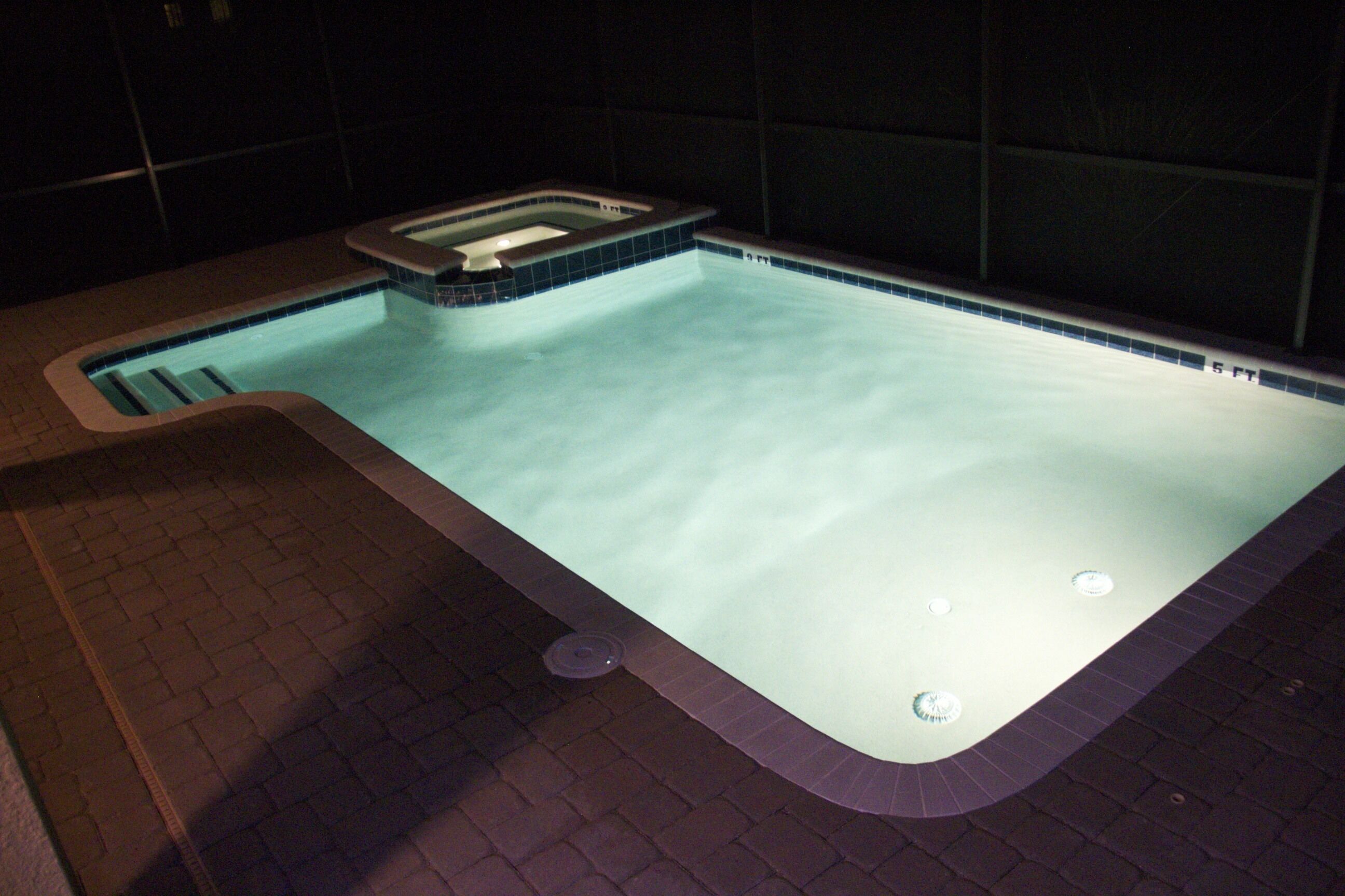 A swimming pool with a tiled edge and a built-in hot tub.