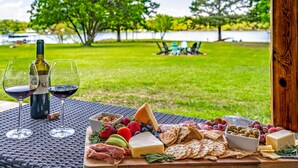 A picnic setup with a variety of cheeses, fruits, and crackers on a table, with a bottle of wine and glasses. - 4th Nt Free! Waterfront Bungalow! Dock | Kayaks (Wills Point)