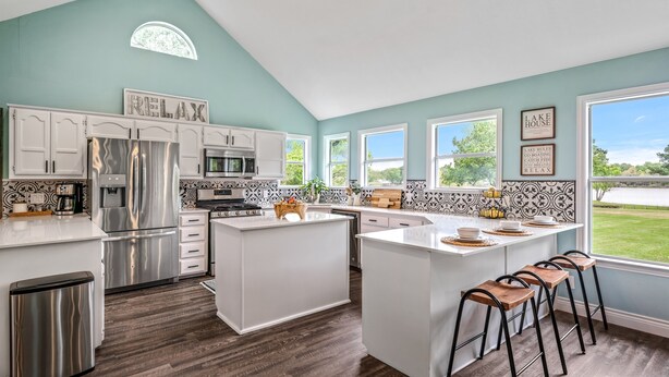 A modern kitchen with white cabinetry, stainless steel appliances, and a central island with bar stools. - 4th Nt Free! Waterfront Bungalow! Dock | Kayaks (Wills Point)