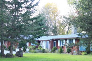 A house with a red exterior, a chimney, and a well-maintained lawn. - Gorgeous All Season Water Front Cabin (Belleville)