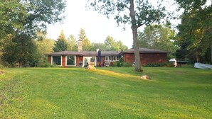 Une propriété résidentielle dotée d’une grande pelouse, d’un garage indépendant et d’une maison avec une cheminée.