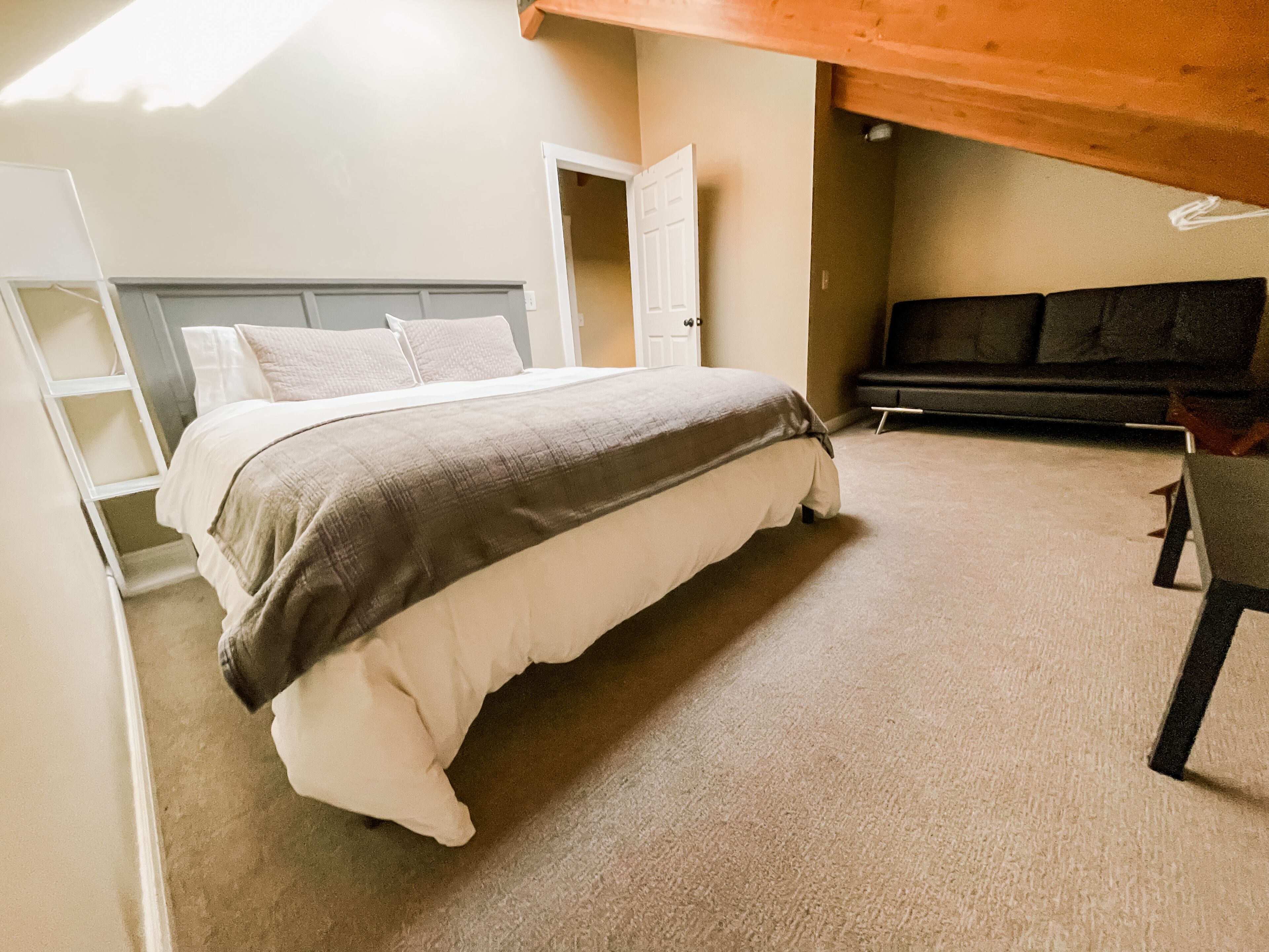 A bedroom with a bed, a bench, and a door.