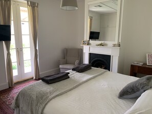 A bedroom with a bed, a chair, a fireplace, and a large mirror. - Vineyard views, large deck, Pet friendly, WiFi, Netflix, Pool, Firepit, Aircon (Spring Farm)