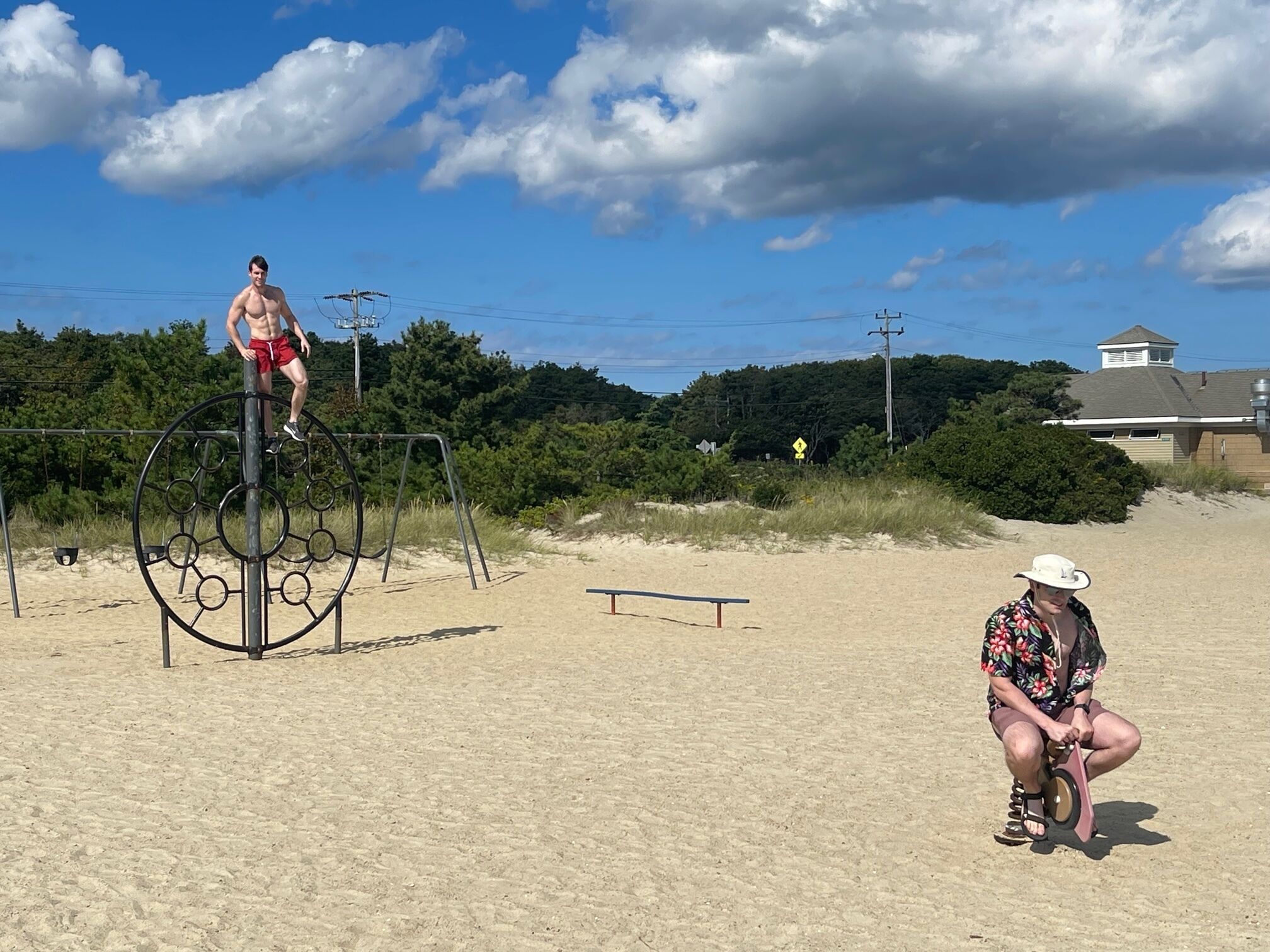 Une plage de sable équipée d’installations de remise en forme, notamment une barre de traction et un banc.