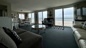 Un salon avec vue sur la plage, un coin repas et un téléviseur.