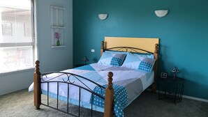 A bedroom with a bed, a window, and a wall-mounted lamp.