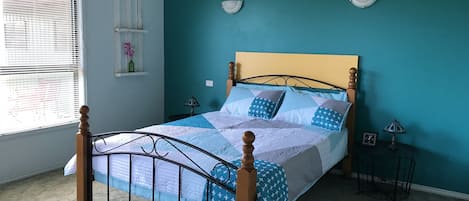 Un dormitorio con una cama, una ventana y una lámpara fijada a la pared.