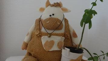 Ein plüschiges Giraffen-Spielzeug sitzt auf einer weißen Oberfläche, neben ihm ein Blumentopf.
