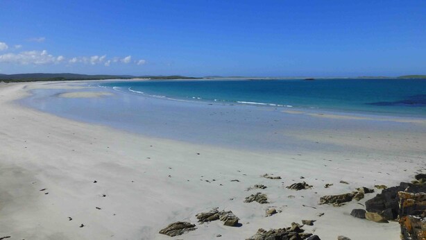 A beach with white sand and clear blue water.