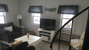 Ein Wohnzimmer mit einer Couch, einem Couchtisch, einem Fernseher und einer Treppe.