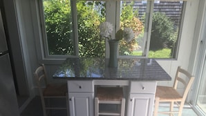 Eine Küche mit einer Granit-Arbeitsplatte, weißen Schränken und zwei gepolsterten Stühlen.