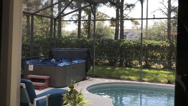 Zona junto a la piscina con un jacuzzi, sillas de descanso y un ventilador de techo.