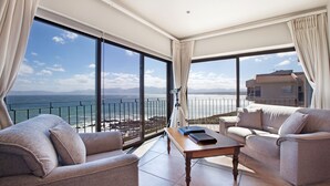 En rummelig balkon med udsigt over ocean og bjerge, møbleret med en sofa og et bord.