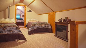 Een slaapkamer met twee bedden, een houten garderobe en een open haard.