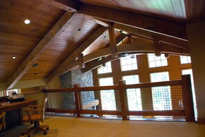 Relax in a spacious room with a high ceiling, featuring a large window and a wooden desk.