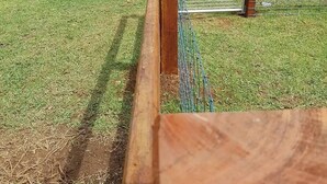 A wooden fence with a metal gate in a grassy area. - Fairmont Cottage (Woodhill)