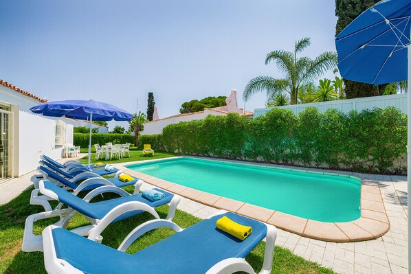 A swimming pool with lounge chairs and umbrellas.