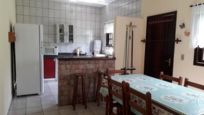 Cocina compacta con refrigerador, microondas y una pequeña zona de comedor con mesa y sillas.