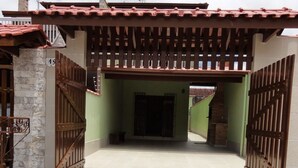 Una entrada porticada con suelo de baldosas que lleva a un edificio con pared verde y tejado de baldosas.