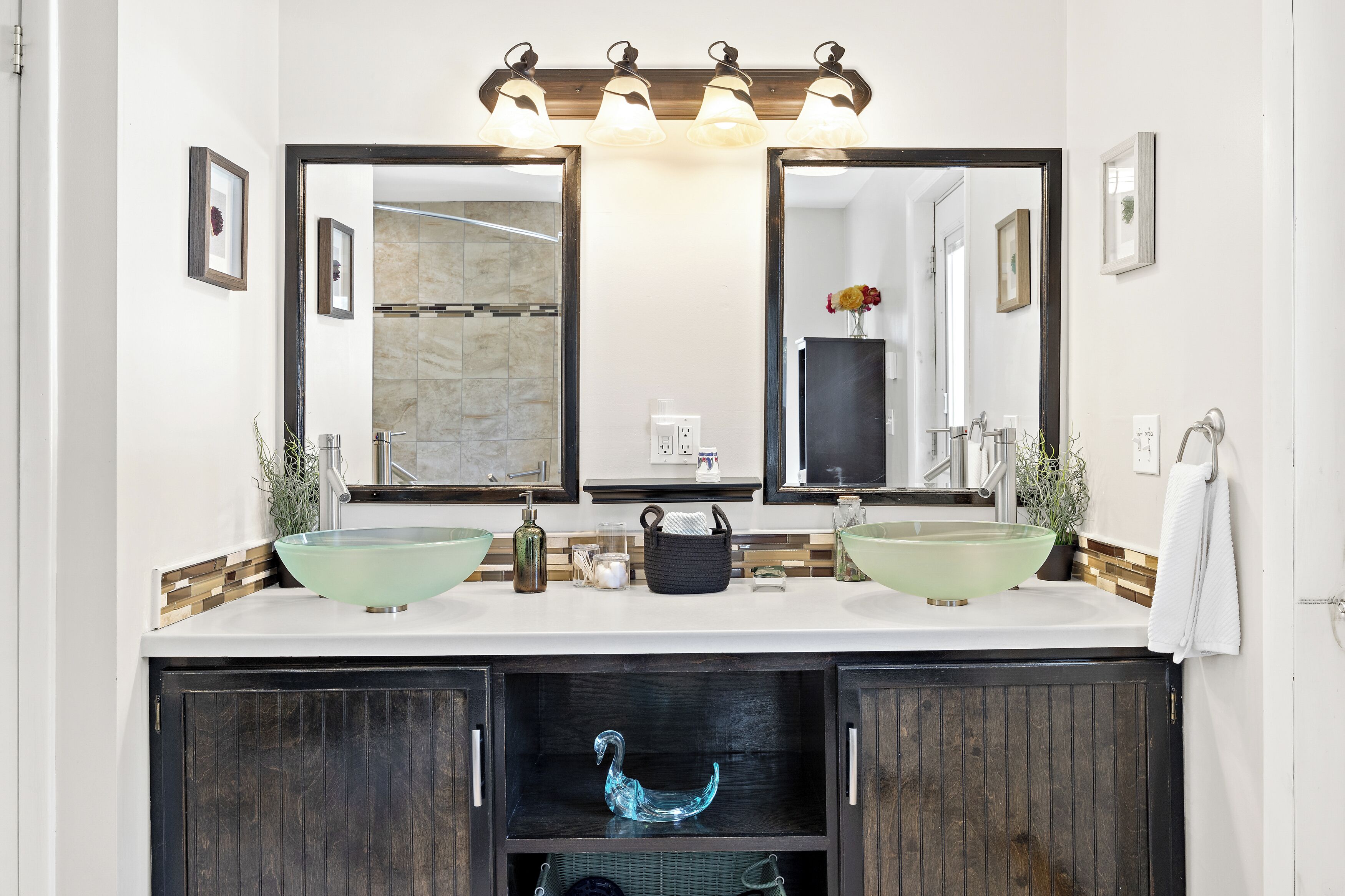 A bathroom with two glass sinks, a large mirror, and a dark wooden cabinet below.